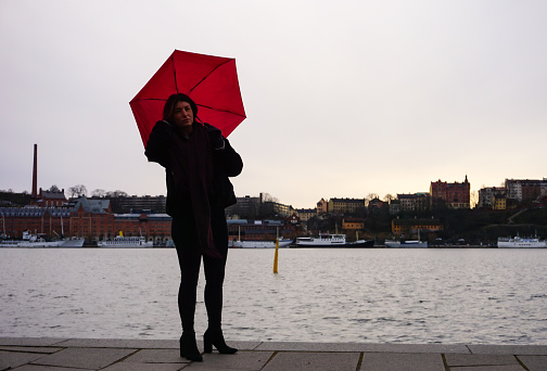 Woman with umbrella standing on promenade against sky
