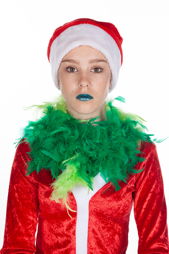 Closeup portrait of expressionless young girl wearing red santa clause hat, christmas grinch isolated on white background. Negative human emotion facial expression