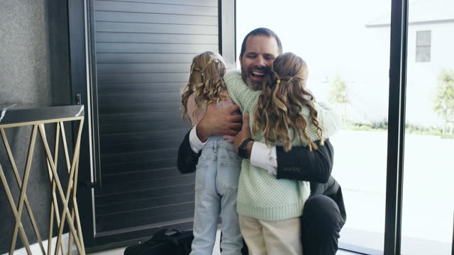 Hug, greeting and a father with children after work, arriving home and kids happy to see dad. Love, affection and a man hugging daughters after coming from job, talking and embracing at the door