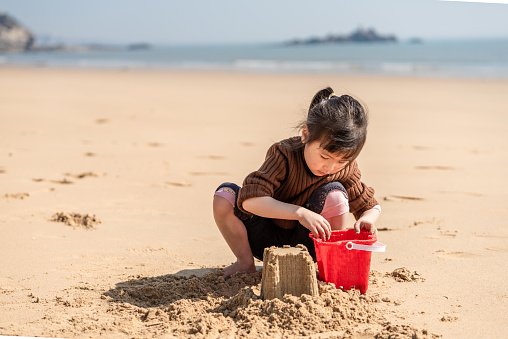 A Chinese girl plays with sand on the beach