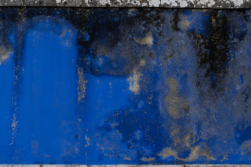 Blue weathered moldy wall with peeling off layers of paint