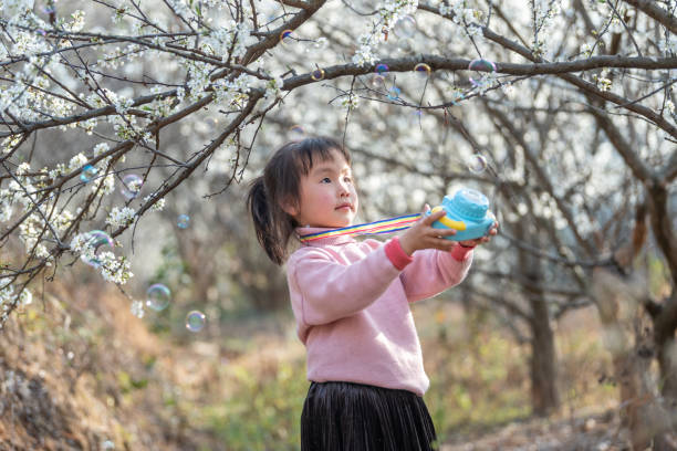 istock A girl plays a bubble machine in the plum forest 1483989865