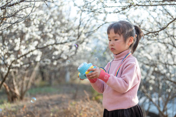 istock A girl plays a bubble machine in the plum forest 1483989870