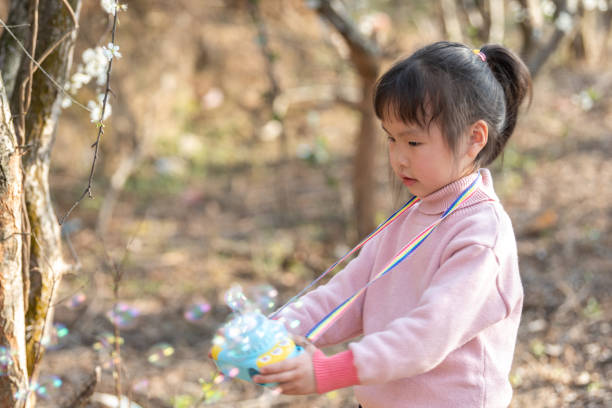 istock A girl plays a bubble machine in the plum forest 1483989919