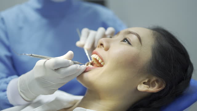 Close Up Of Dentist Examining Female Patient's Teeth