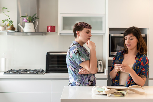 Lesbian couple in the kitchen thinking and wrting the grocery list. Copy space.