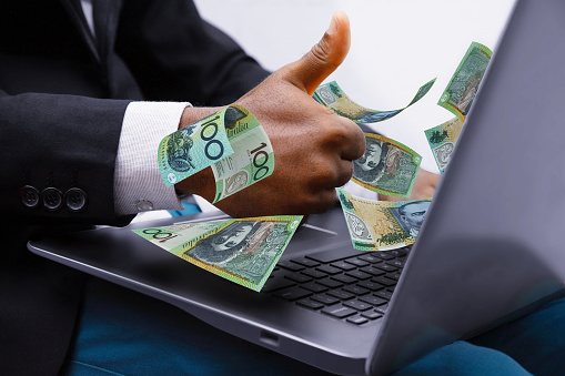 Australian Dollar notes coming out of laptop with Business man giving thumbs up, Financial concept. Make money on the Internet, working with a laptop