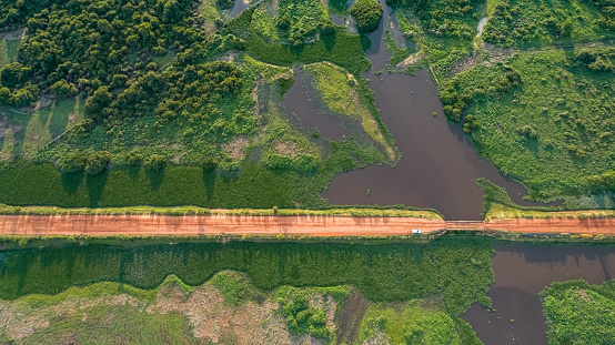 Aerial view of Transpantaneira dirt road crossing a river by a wooden bridge, lush vegetation around, North Pantanal Wetlands, Mato Grosso, Brazil