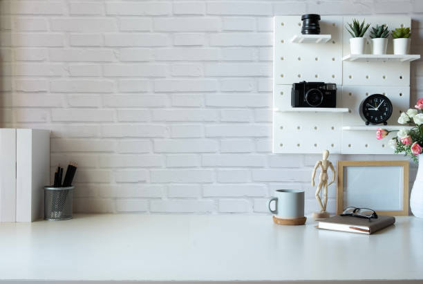 istock Creative workplace with books, picture frame, retro camera and coffee cup on white table. Copy space for text. 1484005420