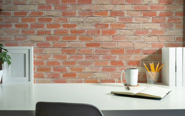 istock Stylish workplace with books, picture frame, retro camera and coffee cup on white table. Copy space for text. 1484005435