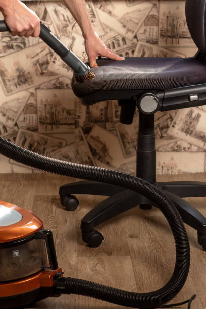 istock Man cleans black office chair with vacuum cleaner. 1484005584