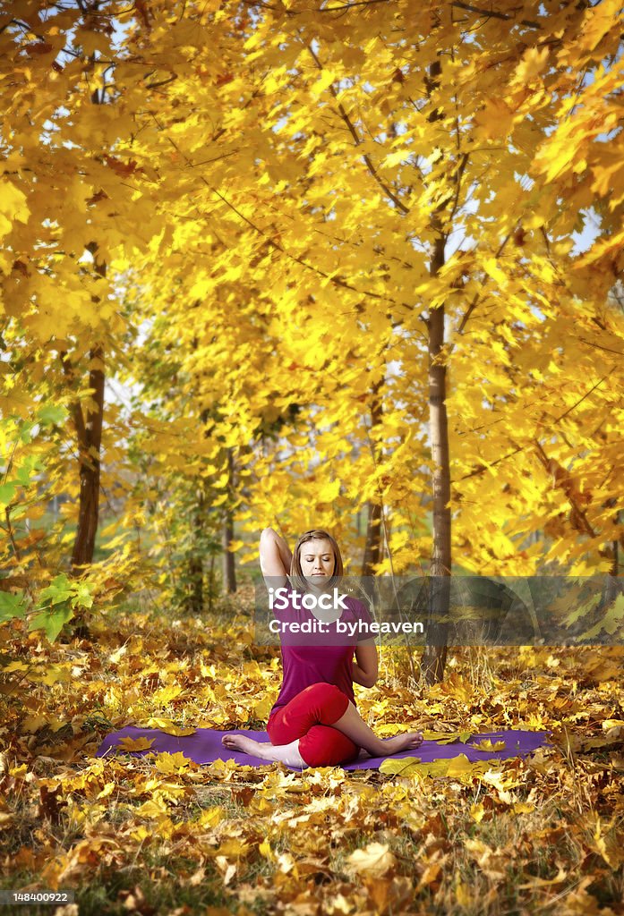 Yoga in autumn Yoga gomukhasana cow pose by concentrate beautiful woman in red cloth and yellow leaves around in the autumn Active Lifestyle Stock Photo