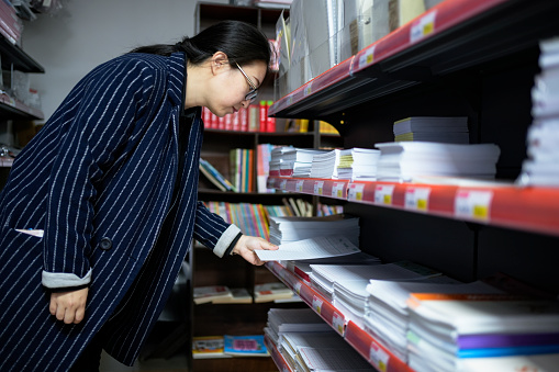 Asian women pick up office supply notebooks
