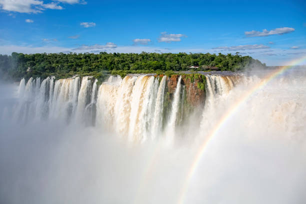istock View to Devil`s Throat and Salto Union with rainforest, blue sky, white clouds and small rainbow, Iguazu Falls, Argentina 1484017075