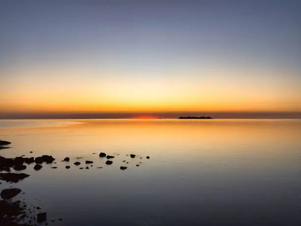 Photo of sunset over ocean with mysterious rocks