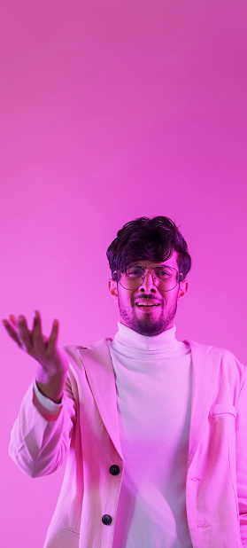 Stunned face. WTF expression. Skeptic shock. Pink color neon light annoyed astonished man showing disgust confusion with shrug gesture on empty space background.