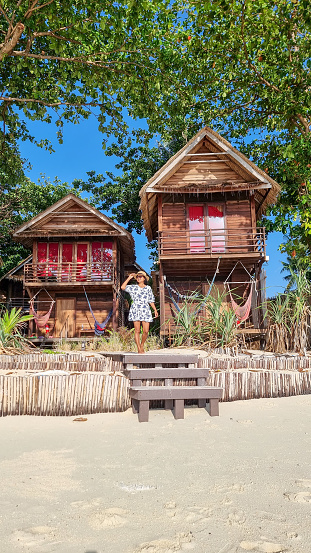 women in front of a bamboo hut bungalows on the beach in Thailand. simple backpacker accommodation in Thailand
