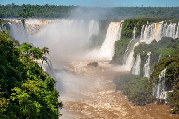 istock View to Devil`s Throat and Iguazu Falls gorge with brown river, white cascading falls and lush green rainforest in sunshine 1484019184
