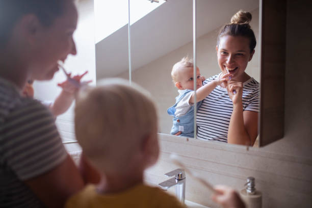 istock Mother and two sons look at each other in the mirror while brushing their teeth 1484019799