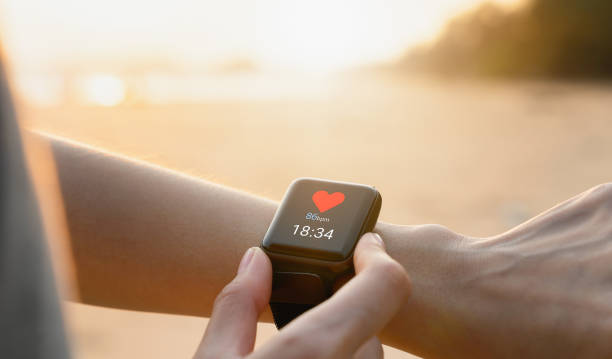 Hand wearing a smartwatch and checking active lifestyle and using fitness tracker outdoor on the beach. stock photo