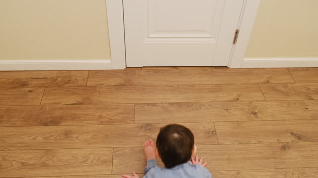 Funny baby crawls backwards while sitting on the floor. Child moves unusually on the floor in the home living room. Kid about two years old (age one year nine months)