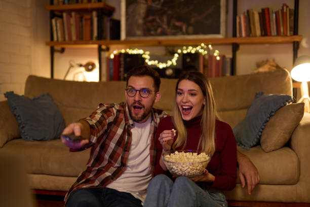 istock Young romantic couple watching TV at home 1484023855