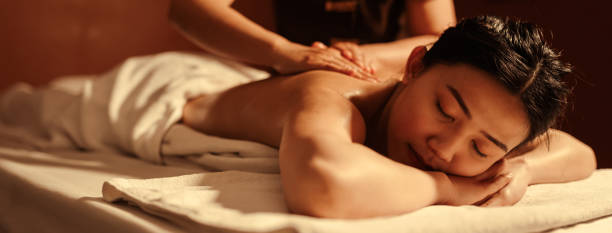 релаксация азиатская женщина-клиент получает услугу ароматерапевтического массажа с массажисткой в спа-салоне. - thai ethnicity massaging thailand thai culture стоковые фото и изображения