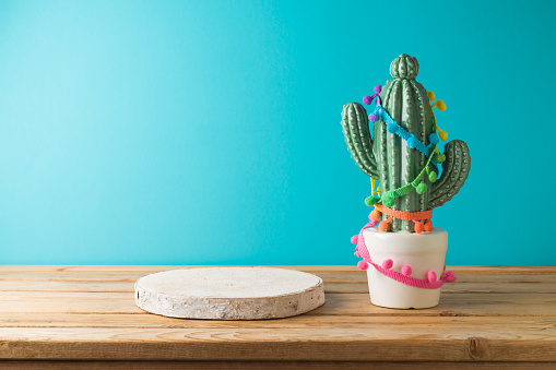 Empty wooden podium with  cactu decoration on wooden table over blue background. Cinco de Mayo Mexican holiday celebration
