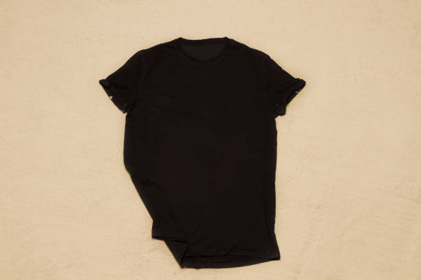 istock Sand beach texture background. Mockup black summer t-shirt copy space. Blank template shirt Top view. Summertime clothing. Flat-lay closeup tshirt on seashore. Beachtime holidays 1484033378