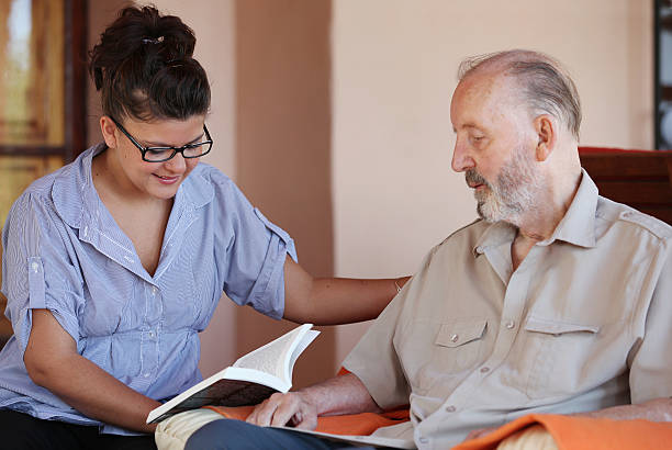 carer reading to senior stock photo