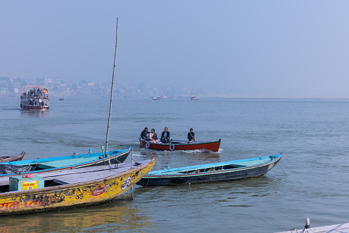 Varanasi, Uttar Pradesh, India - November 2022: Tourists enjoying boat ride in the river ganges during early morning at assi ghat.