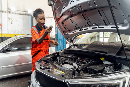 mechanic student working in garage at FE college, young woman learning mechanical skills