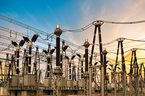 High voltage transmission towers with red glowing wires against blue sky - Energy concept