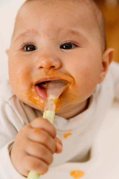istock Cheerful Baby eating her first meal 1484055400
