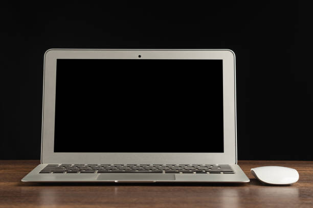 istock Laptop with blank screen and mouse on a wooden table with a black background. 1484055493