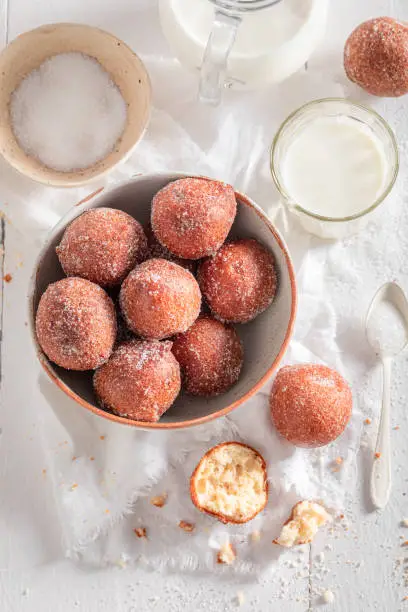 Photo of Hot mini doughnuts with caster sugar and milk.