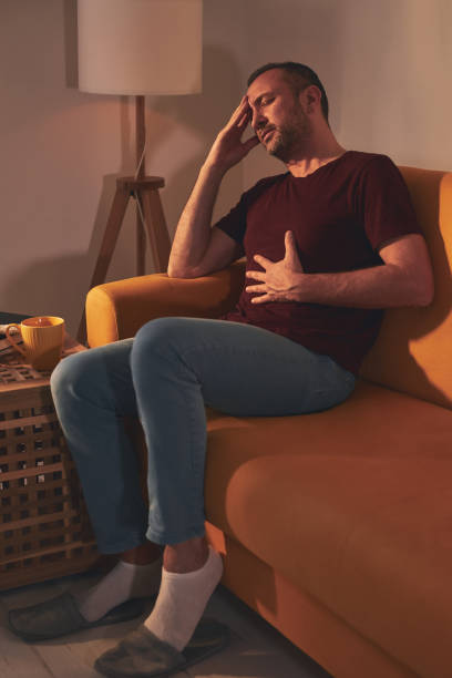 istock Man with stomach and head pain at home. 1484057384