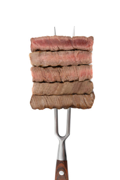 istock Slices of beef steak on meat fork isolated on white background. 1484057524