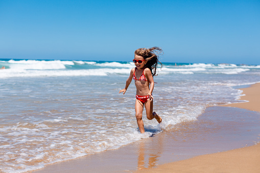Girl enjoys her summer and running on the beach