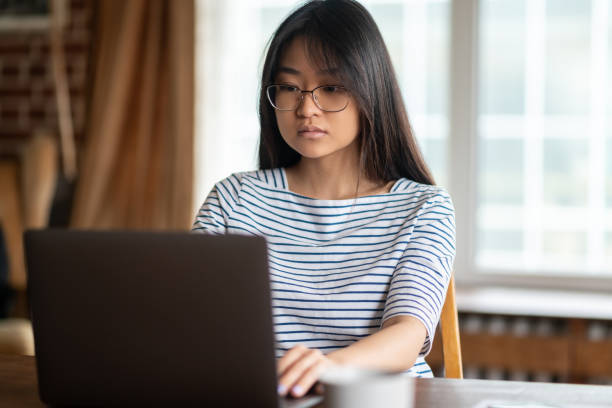 istock Dark-haired young woman working on laptop and looking involved 1484057867