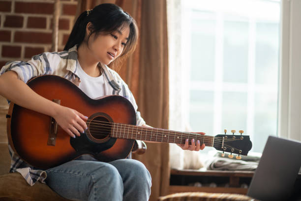 istock Young asian girl having an online class on playing guitar 1484058043