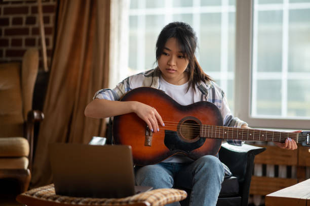 istock Young asian girl having an online class on playing guitar 1484058063