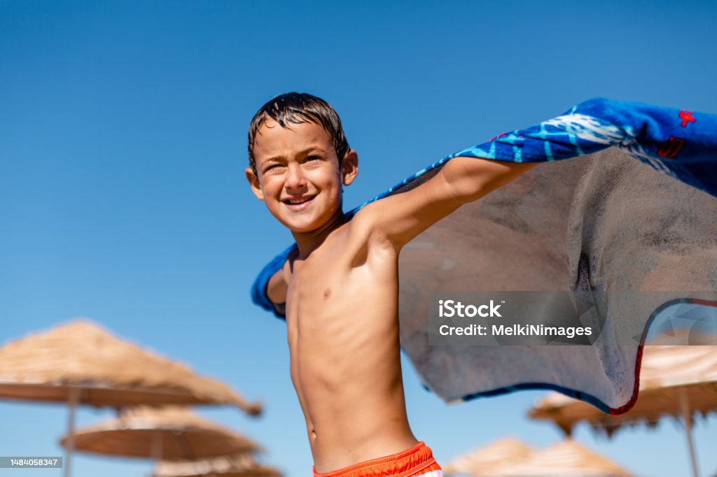 Boy playing superhero with towel on the beach Beach Stock Photo