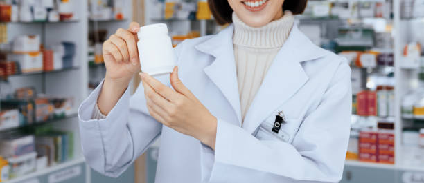 istock Closeup young asian pharmacist pill bottle mockup at qualified pharmacy 1484059978
