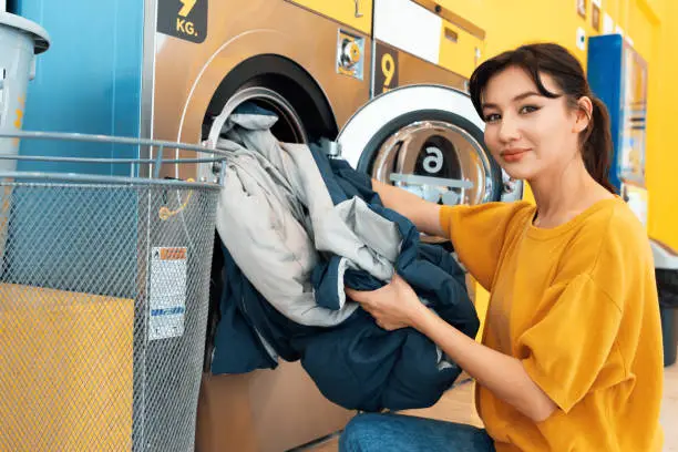Photo of Asian people using qualified laundry machine in the public room.
