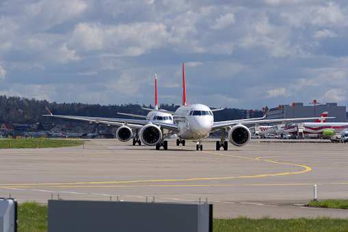 Helvetic Airways and Swiss airplanes taxiing in a row at Swiss Airport Zürich Kloten on a sunny spring day. Photo taken April 14th, 2023, Kloten, Canton Zurich, Switzerland.