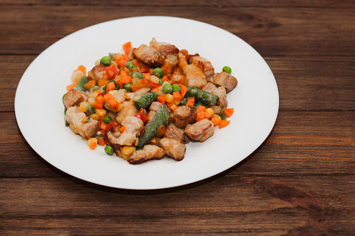 Stewed vegetables with meat, vegetables carrots, peas, beans in a plate.