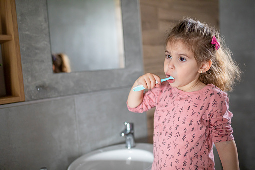 Little girl brushing her teeth in a bathroom at home
