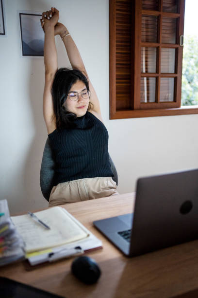 istock Young woman stretching while working long hours at home office 1484079161