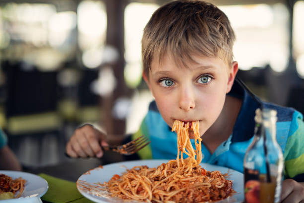 istock Cute little boy having fun eating spaghetti 1484079187